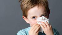 playful child using tissue to clean his nose from cold