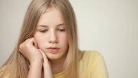 Studio portrait of a blonde teen girl in a yellow t-shirt on a beige background