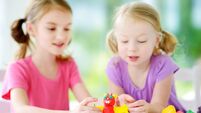 Two cute little sisters having fun together with modeling clay at a daycare. Creative kids molding at home. Children play with p