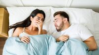 Annoyed woman suffering because of the bad breath of her husband in bed