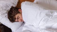 Cute teenage boy sleeping in white bedding, covered to ears
