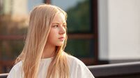 Outdoors portrait of 15 year old blonde teen girl with long hair in white t-shirt