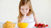 Little girl eating cereal with milk