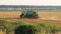 a big tractor with a manure spreader is injecting a field in the dutch countryside