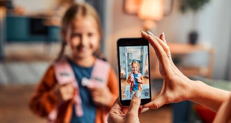 Saving memories in gadget. Selective focus on display of telephone recording video with first grade girl
