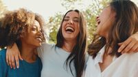 Happy multiethnic young womens talking while sitting on park bench on summer day outdoors, Panorama. Group of girls talking and