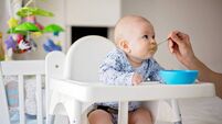 Cute little baby boy, eating mashed vegetables for lunch, mom feeding him