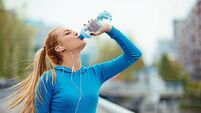 Sporty Young Woman Drinking Water On Bridge