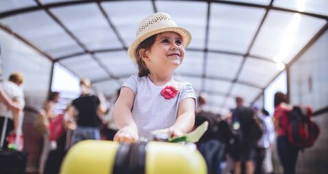 Cheerful and excited toddler with her coffer on a airport