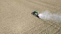 Tractor spreading agricultural lime in a field seen from above