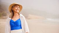 Portrait of cheerful senior woman wearing sunhat on summer vacation, looking away