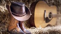 Cowboy hat guitar and boots in barn, country music festival live concert or rodeo background
