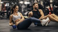 Fitness couple is doing kettlebell twist in a gym togehter.