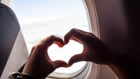 Hands Forming a Heart Shape Near an Airplane Window During Flight