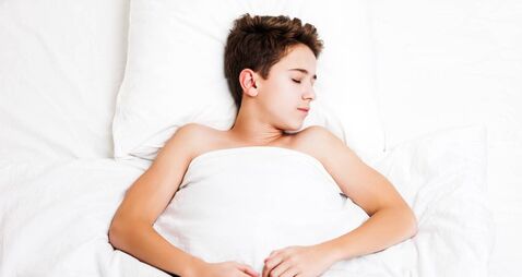 Happy handsome sleeping child boy lying bed and resting