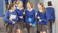 Cheerful female students wearing blue school uniforms walking in locker room