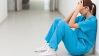 Nurse sitting in a corridor while holding her head