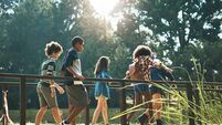 Shot of a group of teenagers walking across a bridge in nature at summer camp