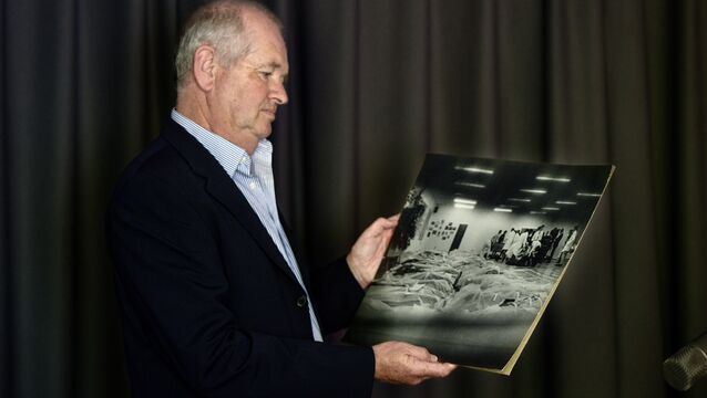 <p>Denis Minihane, retired Irish Examiner and The Echo staff photographer, holds a print of the haunting image he captured in June 1985, showing the bodies of Air India Flight 182 victims laid out in a makeshift Cork morgue. The photograph became a defining moment in his career and remains a stark visual record of the tragedy. Picture: Chani Anderson</p>