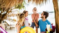 iStock-2157393175.jpg Happy parents having fun with their small kids in a beach bar.