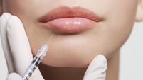 Close up of woman receiving botox injection in lips