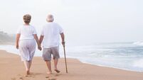 senior couple hand in hand walking on beach
